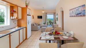 A modern kitchen with a dining area, a sofa, and a view of the sea. - Villa Yiotta in Paxi (Paxos)