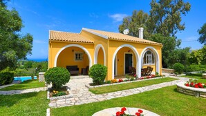 A yellow villa with a stone pathway, outdoor seating, and a pool. - Villa Joanna in (Corfu)