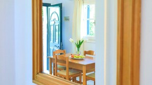 A dining area with a wooden table and chairs, a vase with flowers, and a plate of fruit. - Villa Joanna in (Corfu)