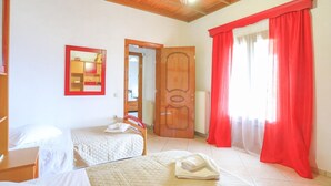 Quarto com duas camas, teto de madeira, espelho com moldura vermelha e uma porta.