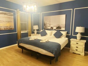 A neatly arranged bedroom with a bed, bedside tables, a bench, and artwork on the walls. - Luxurious 12BR 11.5BA independent self-contained large villa (Kissimmee)