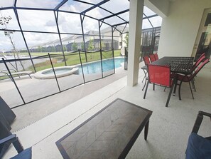 A covered patio area with a pool, outdoor furniture, and a view of a residential neighborhood. - Luxurious 12BR 11.5BA independent self-contained large villa (Kissimmee)