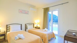 A hotel room with two beds, a small desk, and a balcony with a view. - Villa Anamari in (Corfu)