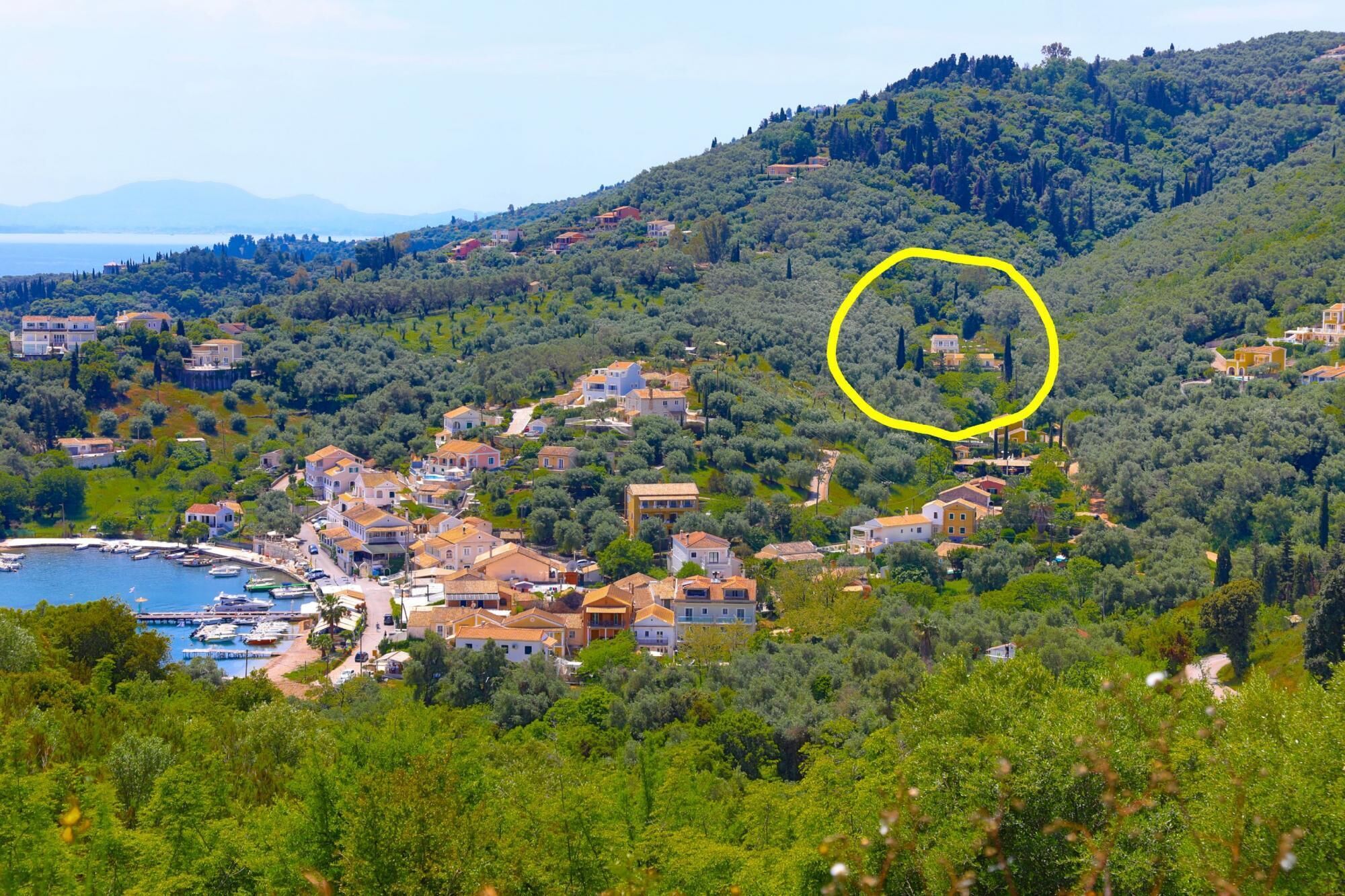 Un pueblo costero con casas rodeadas de vegetación y un puerto deportivo.