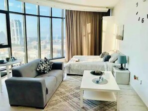 Enjoy a city view from the large window in this stylish room featuring a comfortable bed, a sofa, and a coffee table.