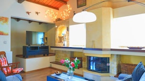 A cozy living room with a fireplace, a television, and a comfortable seating area. - Villa Kristefi in Kato Korakiana (Corfu)