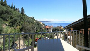 A balcony with a view of a coastal area, including trees and buildings. - Alexandra Apartment in Katavolos (Corfu)