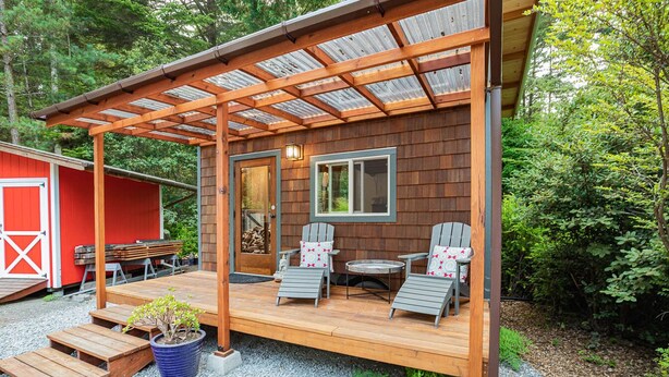 A wooden deck with outdoor seating and a pergola. - Charming Tiny House nestled in the redwoods, less than a mile from the beach. (Fort Bragg)