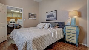 A bedroom with a bed, a dresser, a lamp, and a painting on the wall.