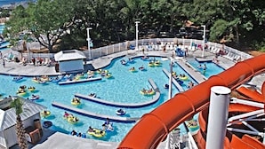 A water park with multiple pools, a large water slide, and a surrounding fence. - 4 bed/4Baths 2 mins. to ocean on golf cart -Free Waterpark with your stay! (Myrtle Beach)