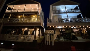 A two-story building with balconies, outdoor seating, and a covered area with tables and chairs. - 4 bed/4Baths 2 mins. to ocean on golf cart -Free Waterpark with your stay! (Myrtle Beach)