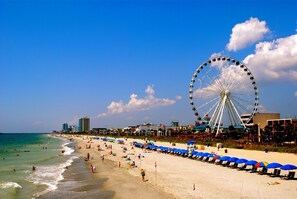 Une plage avec une grande grande roue, un ciel dégagé et une étendue de sable.