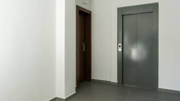 Un pasillo con una puerta de madera y una puerta de ascensor gris.
