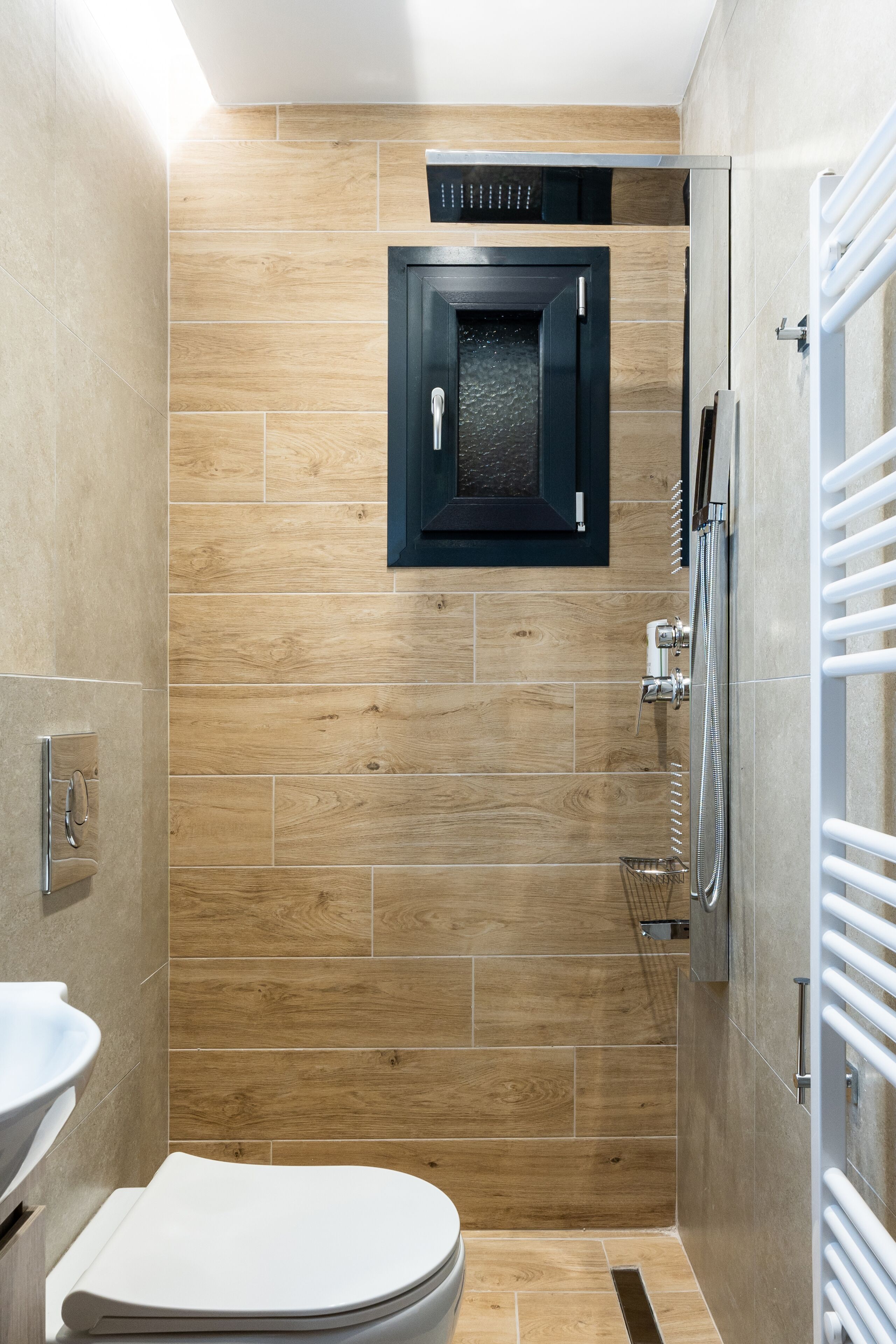 A modern bathroom with a wooden wall, a toilet, a shower, and a built-in cabinet.
