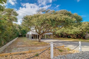 A house with a porch, surrounded by trees and a gravel path.