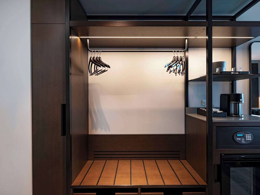 Una kitchenette moderna y compacta equipada con cafetera integrada, microondas y refrigerador pequeño.