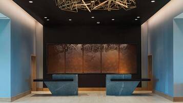A modern reception area with a geometric light fixture, a textured wall, and a reception desk.