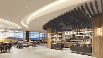 A spacious lobby with a modern design, featuring a large seating area, a central counter with a 'MARKET' sign, and a view of the sky through large windows.