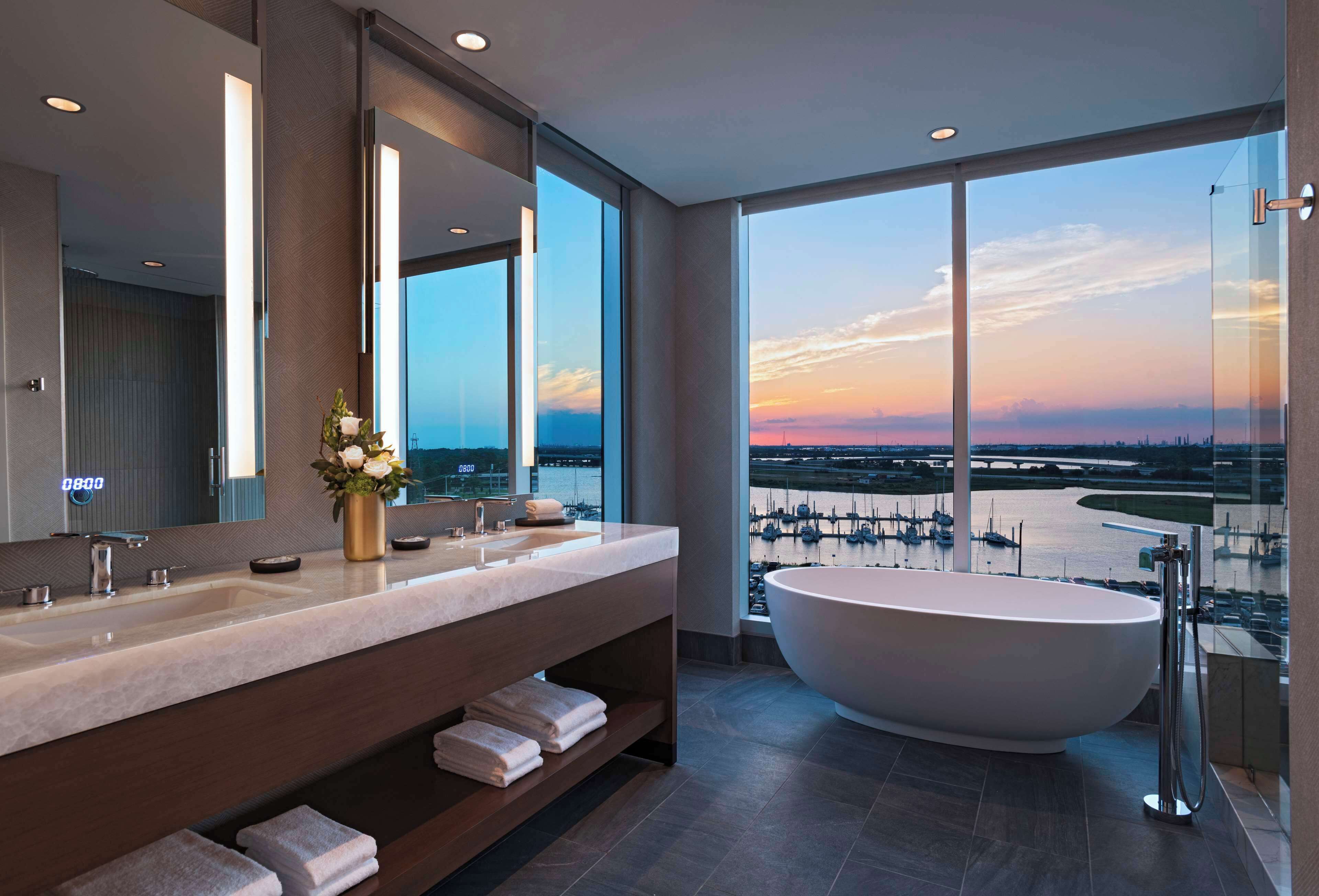 A modern bathroom with a large bathtub, a double sink vanity, and a large mirror.