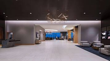 A spacious lobby with a reception desk, seating area, and a modern chandelier.