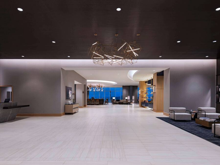 A spacious lobby with a reception desk, seating area, and a modern chandelier.