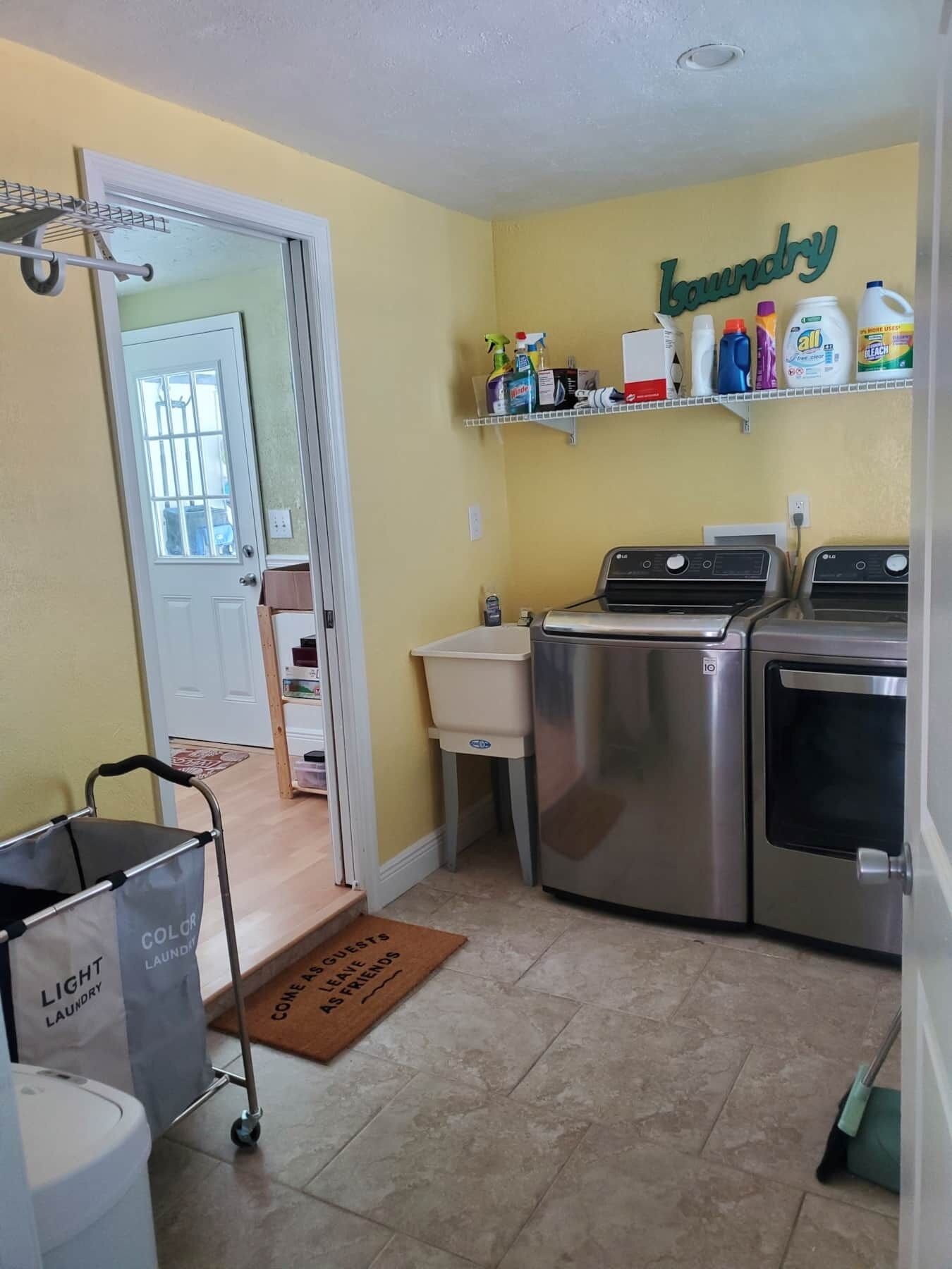 A laundry room with a washing machine, dryer, and shelves with cleaning supplies.