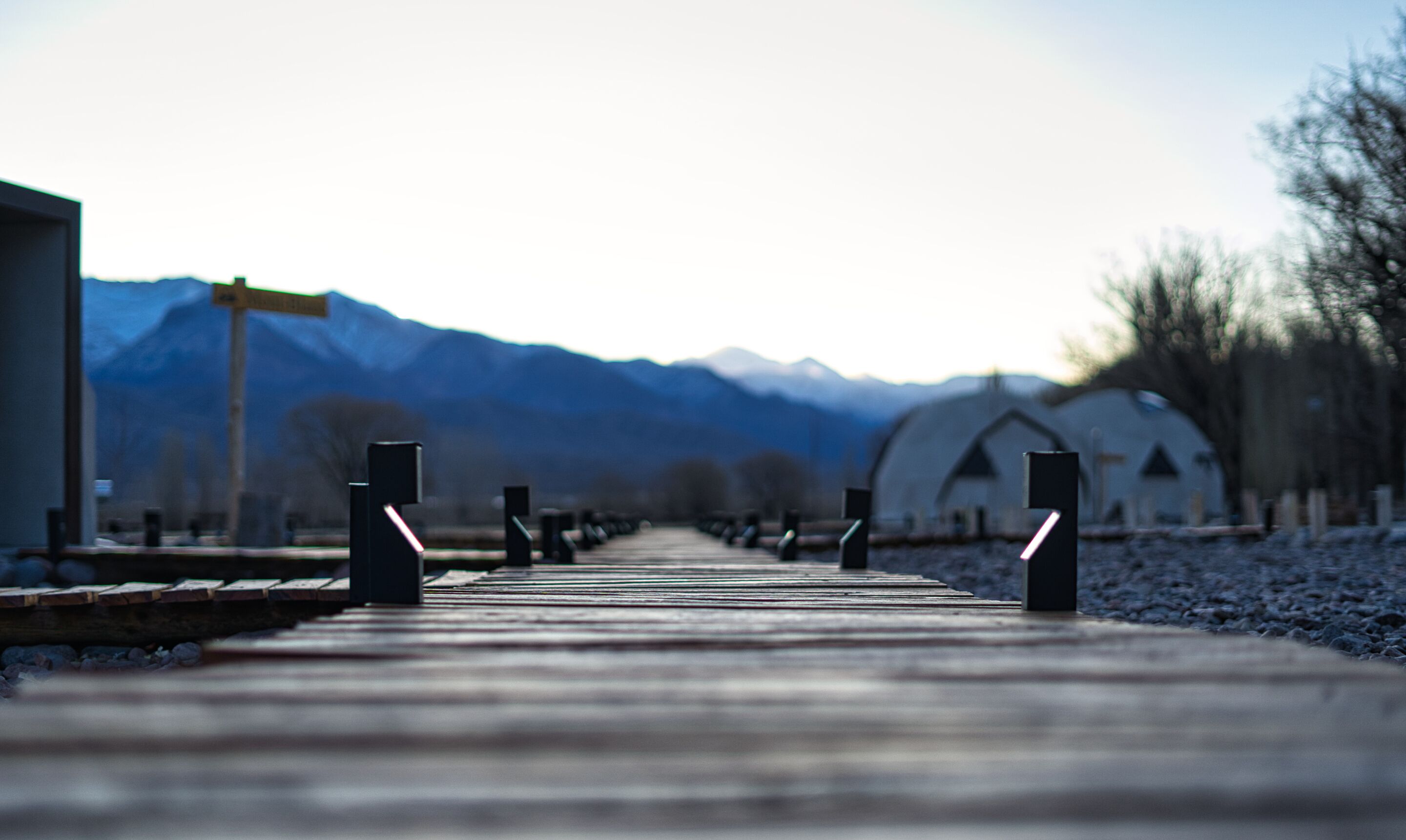 A wooden pathway leading to a building with a mountain backdrop.