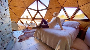 A room with a geometric wooden ceiling, a bed, a chair, and a view of the outdoors. - Cinco Cumbres luxury Camp & Eco Lodge (Uspallata)