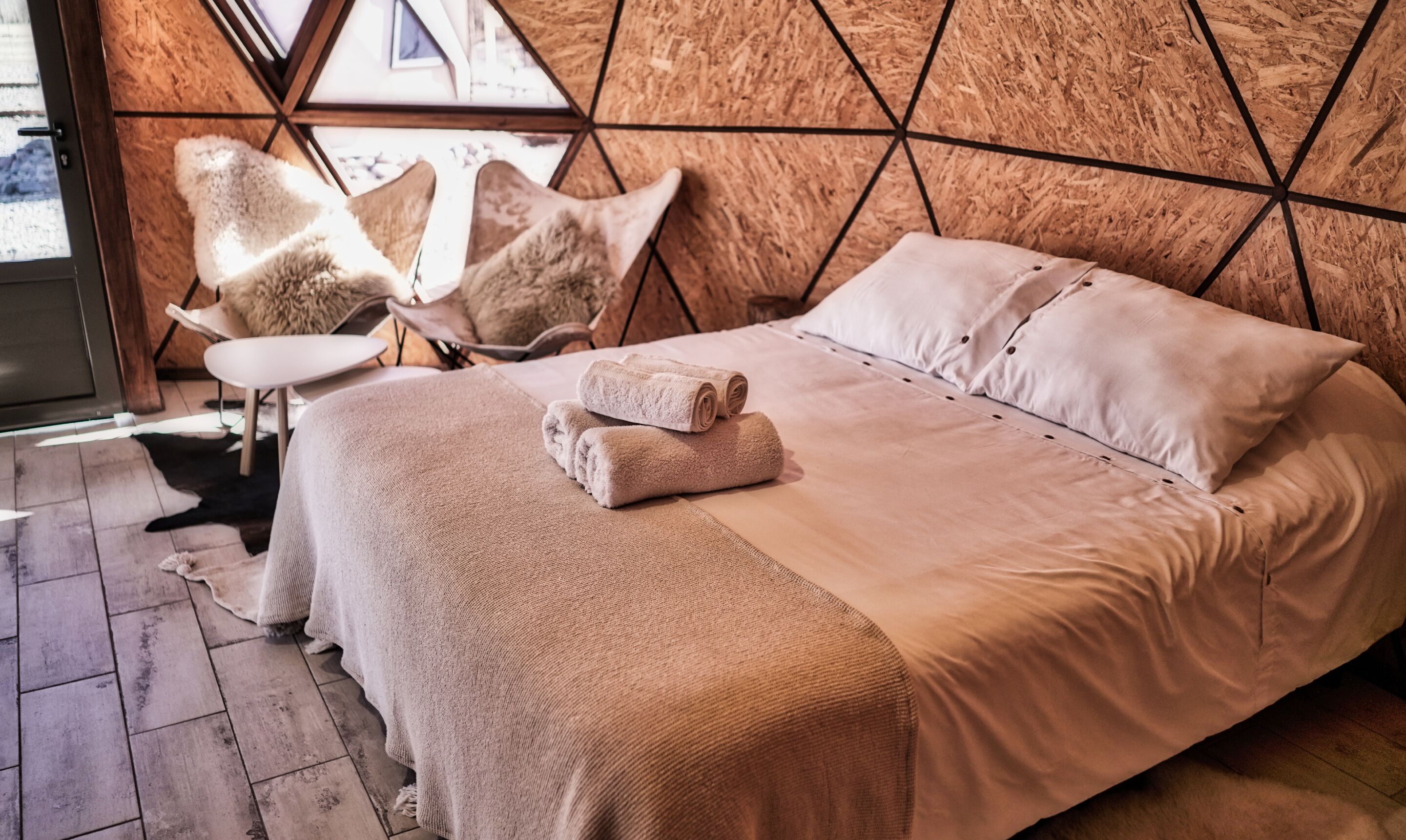Une chambre à coucher avec un lit, des oreillers, une chaise et une couverture.