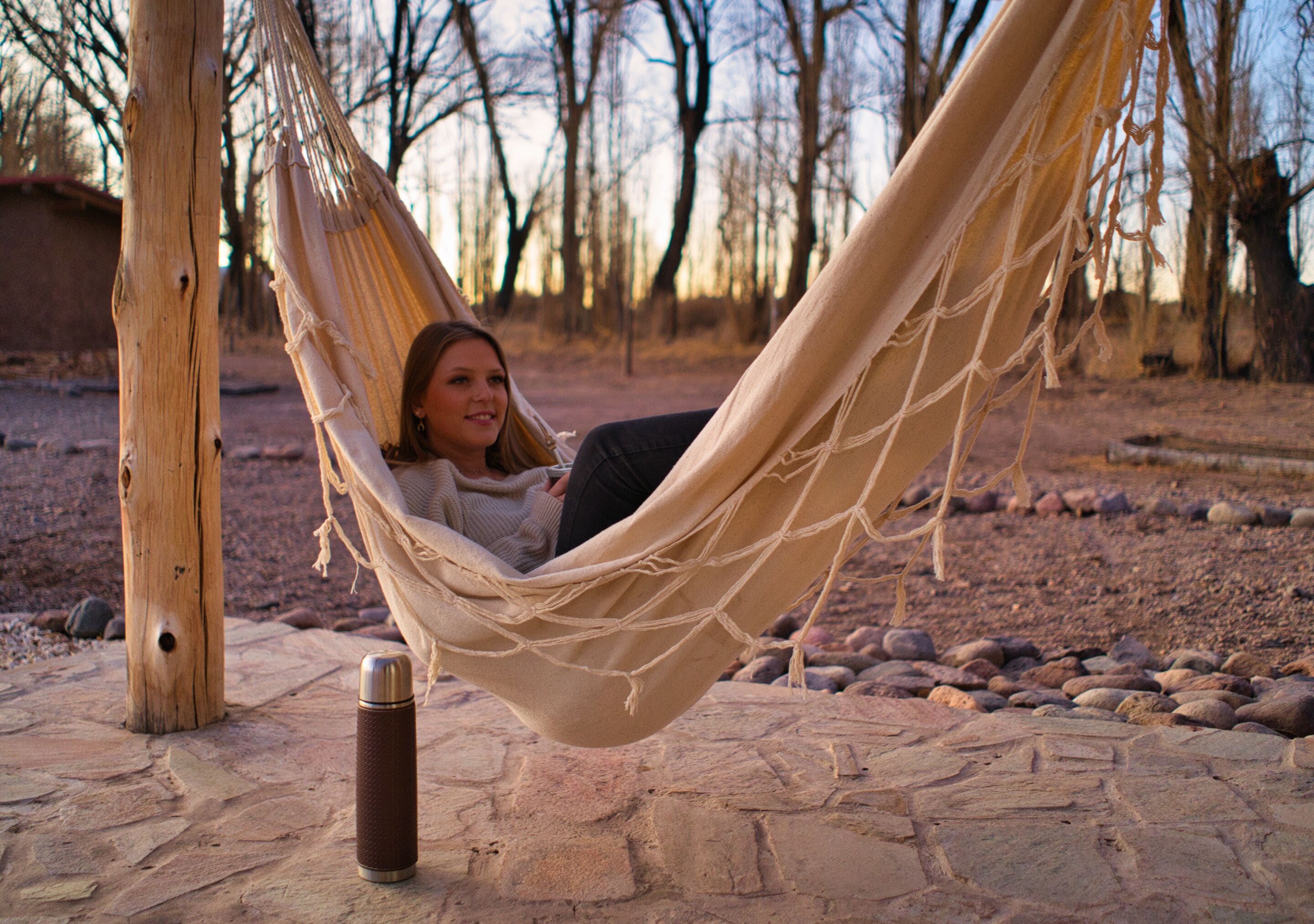A hammock tied between two wooden poles on a stone patio.