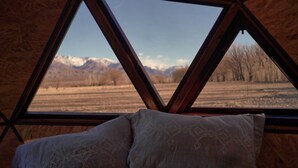 A room with a wooden ceiling and a view of a mountainous landscape through a triangular window. - Cinco Cumbres luxury Camp & Eco Lodge (Uspallata)
