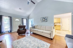 Relax in this inviting living room with a comfortable armchair and sofa, a large area rug, and a beautiful wall art piece.