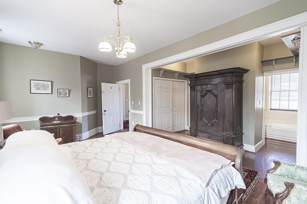 A bedroom with a large bed, a dresser, a vanity, and a wardrobe.