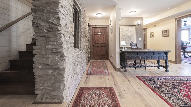 A staircase with a stone wall, wooden steps, and a red carpet leading to a room with a wooden table and chairs. - Light Horse Inn (Harpers Ferry)