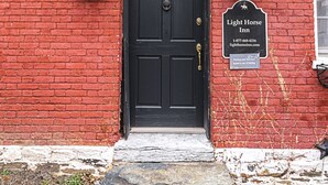 A red brick building with a black door, two wall-mounted lanterns, and a sign for Light Horse Inn. - Light Horse Inn (Harpers Ferry)