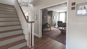 A staircase leading to a living area with a rug, bench, and framed pictures on the wall. - Light Horse Inn (Harpers Ferry)