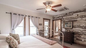 A bedroom with a bed, curtains, a ceiling fan, a dresser, and a rustic wall. - Light Horse Inn (Harpers Ferry)