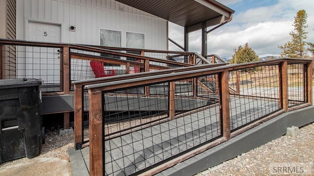 Un bâtiment doté d’un escalier en bois menant à une entrée fermée par un portail.