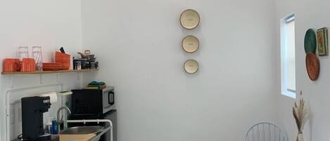 Une cuisine compacte équipée d’un four à micro-ondes, d’un évier et d’un meuble de rangement. On y trouve également un coin repas avec une table et des chaises, ainsi qu’un tapis décoratif.