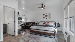 Une chambre à coucher comprenant un lit, un ventilateur de plafond, une table de chevet et une fenêtre.