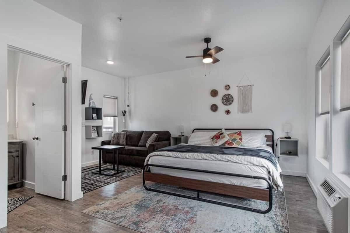 Une chambre à coucher comprenant un lit, un ventilateur de plafond, une table de chevet et une fenêtre.