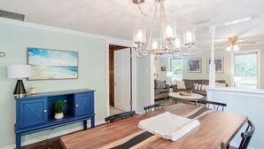 A dining area with a wooden table, blue cabinets, and a chandelier. - On the River! Patio,Yard- Dozing at Dog River (Mobile)
