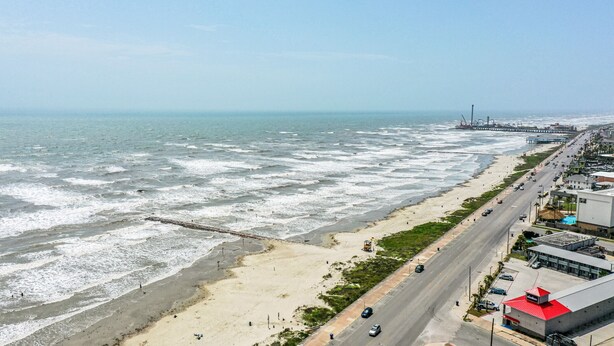 A coastal road with a beach on one side and a commercial area on the other. - Blue Mermaid! Beautiful home 4 blocks from the beach! (Galveston)