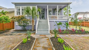 A two-story house with a front porch, a staircase, and a garden with various plants. - Blue Mermaid! Beautiful home 4 blocks from the beach! (Galveston)