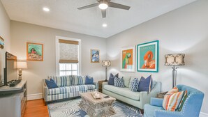 A living room with two sofas, a coffee table, and a TV stand. - Blue Mermaid! Beautiful home 4 blocks from the beach! (Galveston)