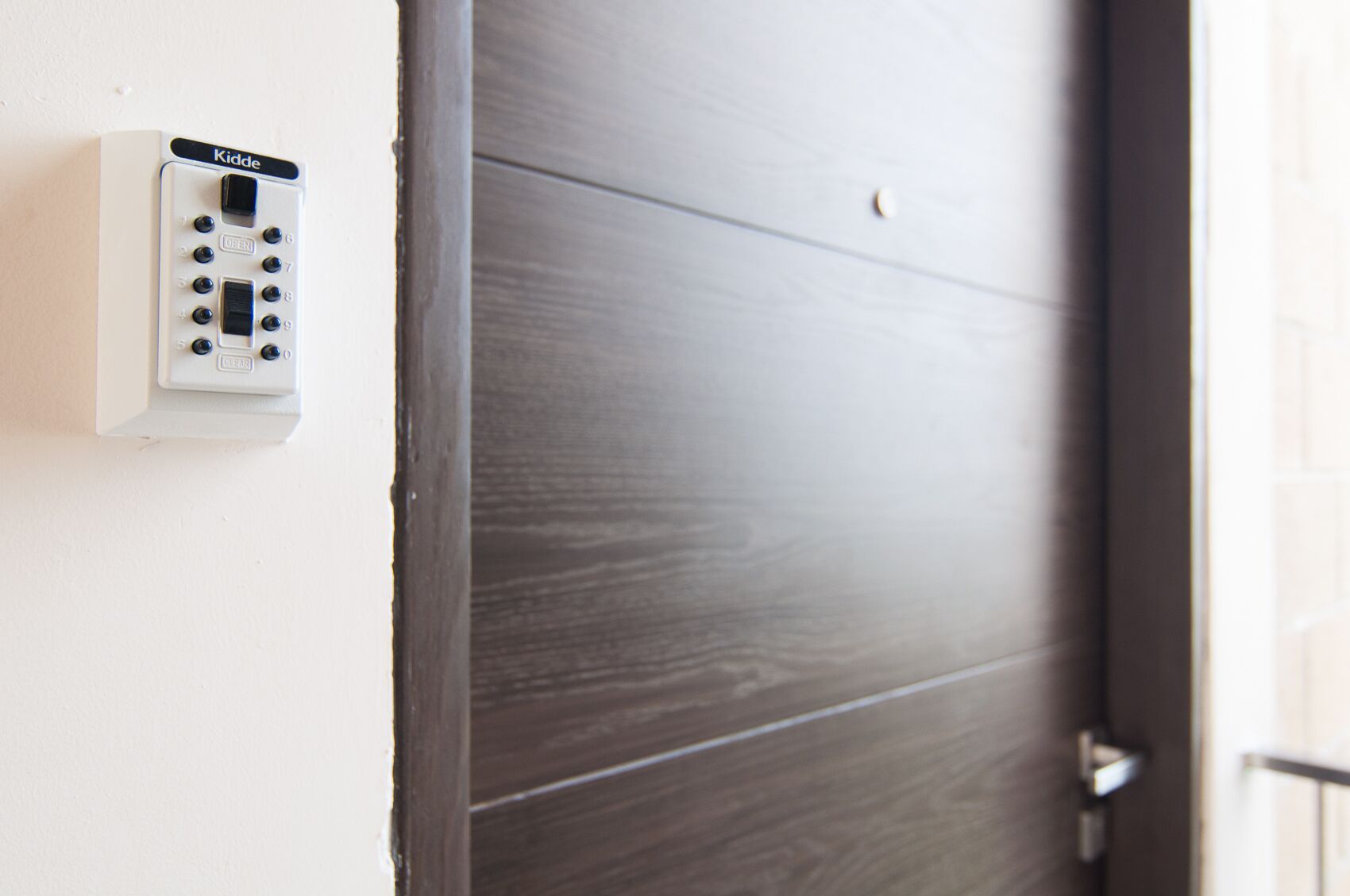 Une porte équipée d’un système d’interphone blanc, marqué du nom « Kidde », fixé au mur.