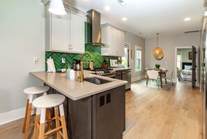 Una cocina moderna con una isla central, taburetes de bar y un comedor con mesa y sillas.