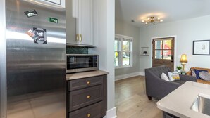 Eine moderne Küche mit einem Edelstahl-Kühlschrank, einer Mikrowelle und dunklen Holzschränken.