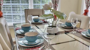 A dining table set with blue plates, bowls, and wine glasses, with a white flower centerpiece.