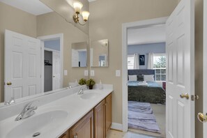 A modern bathroom with dual sinks, a large mirror, and a walk-in closet.